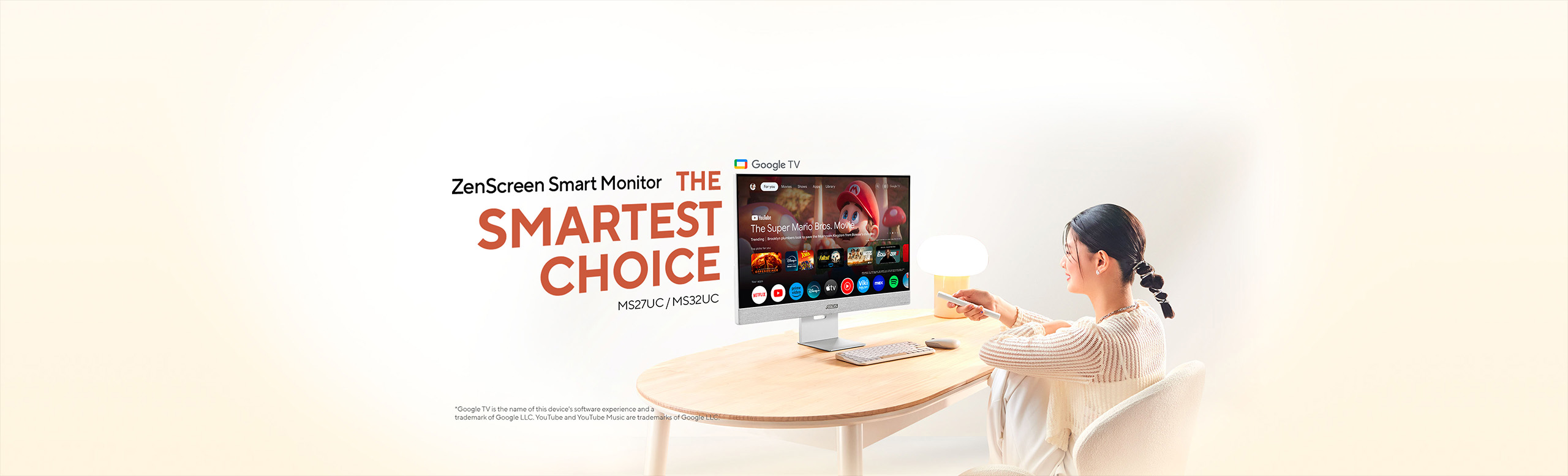 Lifestyle scene showing a woman   at a light‑wood table using a remote to control an ASUS ZenScreen Smart   Monitor (MS27UC / MS32UC) displaying the Google TV interface under the headline “ZenScreen Smart Monitor – THE SMARTEST CHOICE” on a soft   beige background.