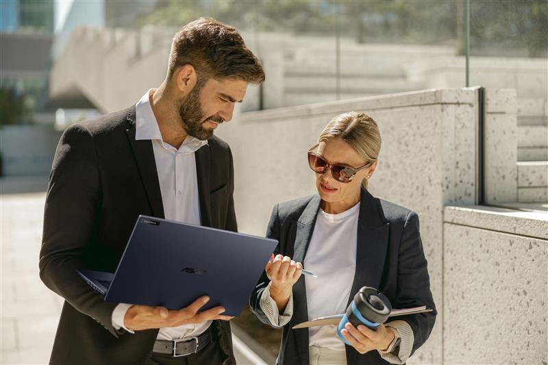 Two people talking outside with a laptop